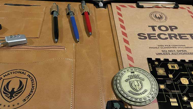 Showing the contents of the folder. Three pens, gold looking decoder disk, top secret file, and a plastic item